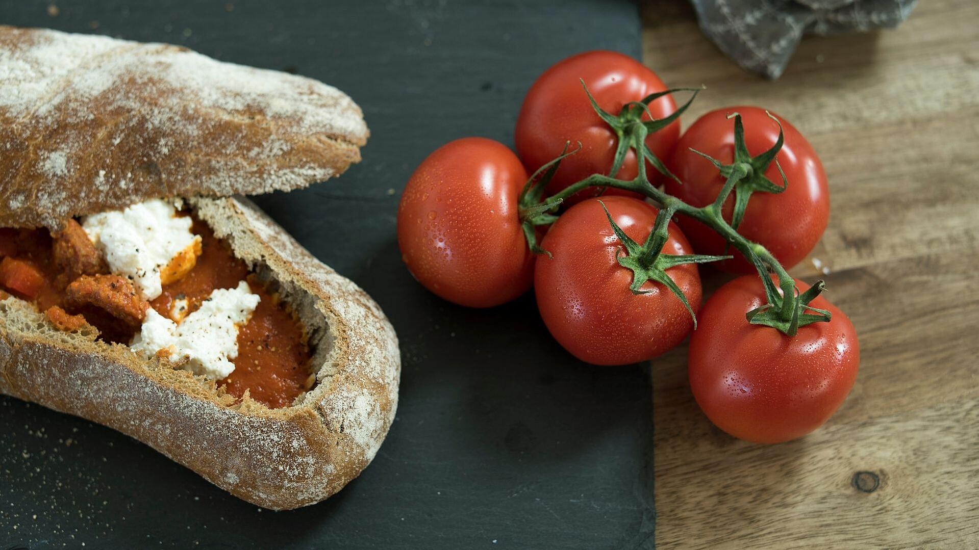 Paprika-Tomatensuppe in einem Ciabatta-Brot serviert, daneben ein Tomatenzweig