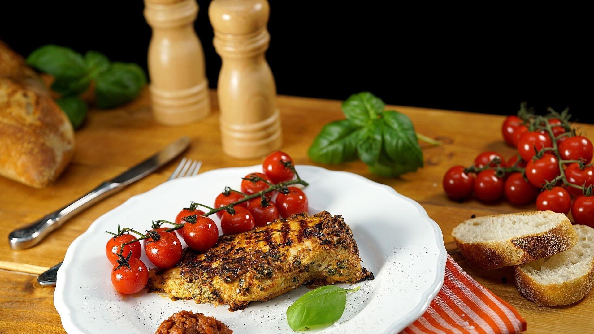 Auf einem Teller liegt ein Hähnchenbrustfilet mit Pesto-Rosso-Joghurt-Marinade
