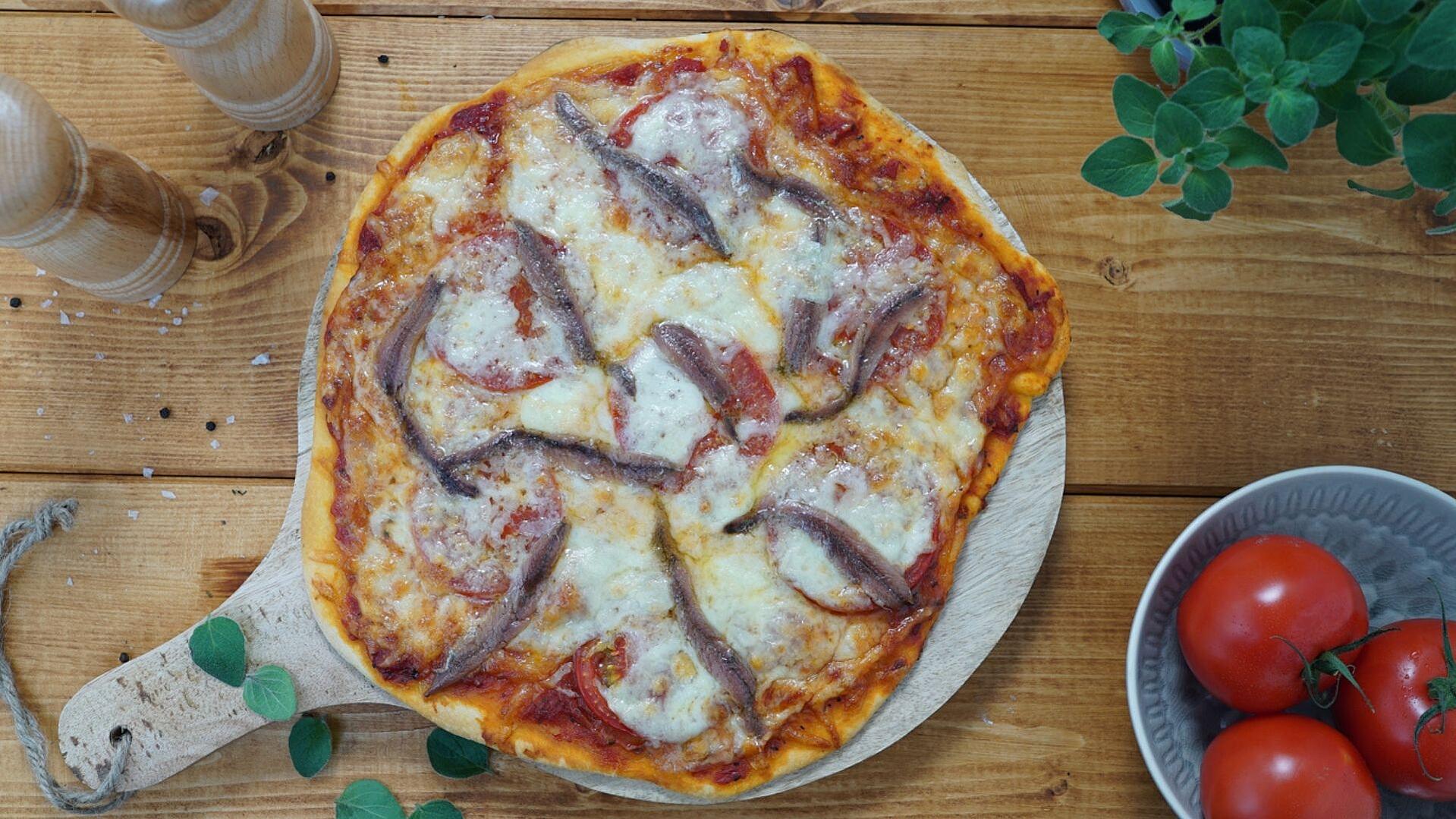 Pizza mit Sardellen auf einem Holzbrett 