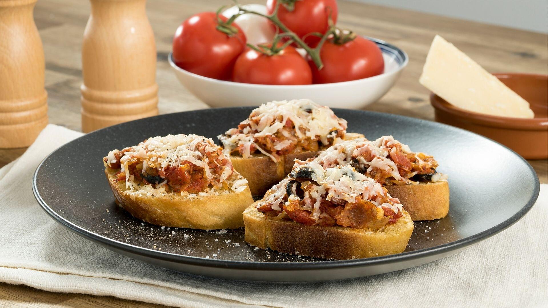 Auf einem Teller sind verschiedene Bruschetta Variationen angerichtet.