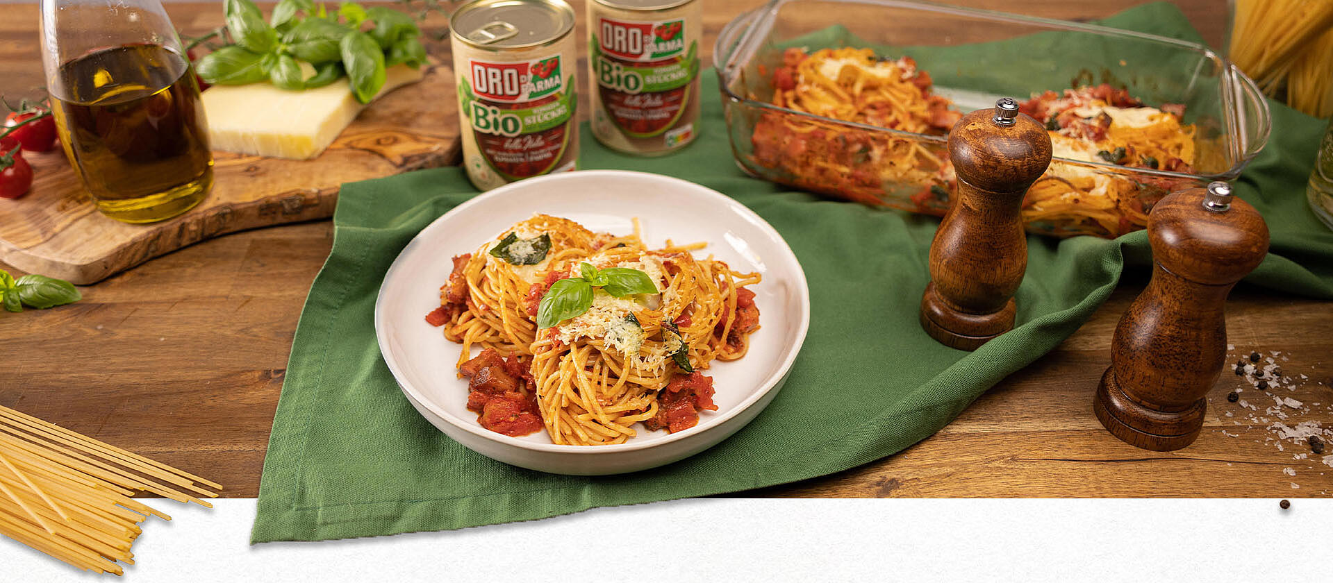 Ein Tisch mit Nudeln, Kräutern und Spaghetti con Provolone e Guanciale in einer Auflaufform aus dem Ofen