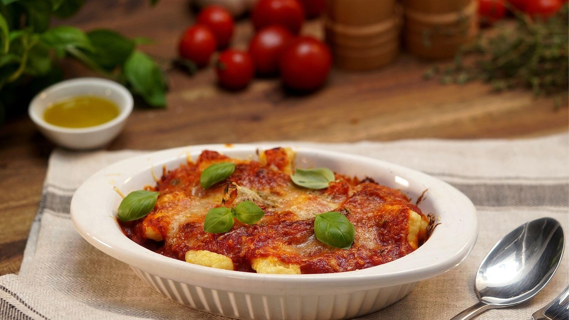 Mit Tomatensauce und Mozzarella überbackene Gnocchi in einer weißen Auflaufform mit Basilikum garniert