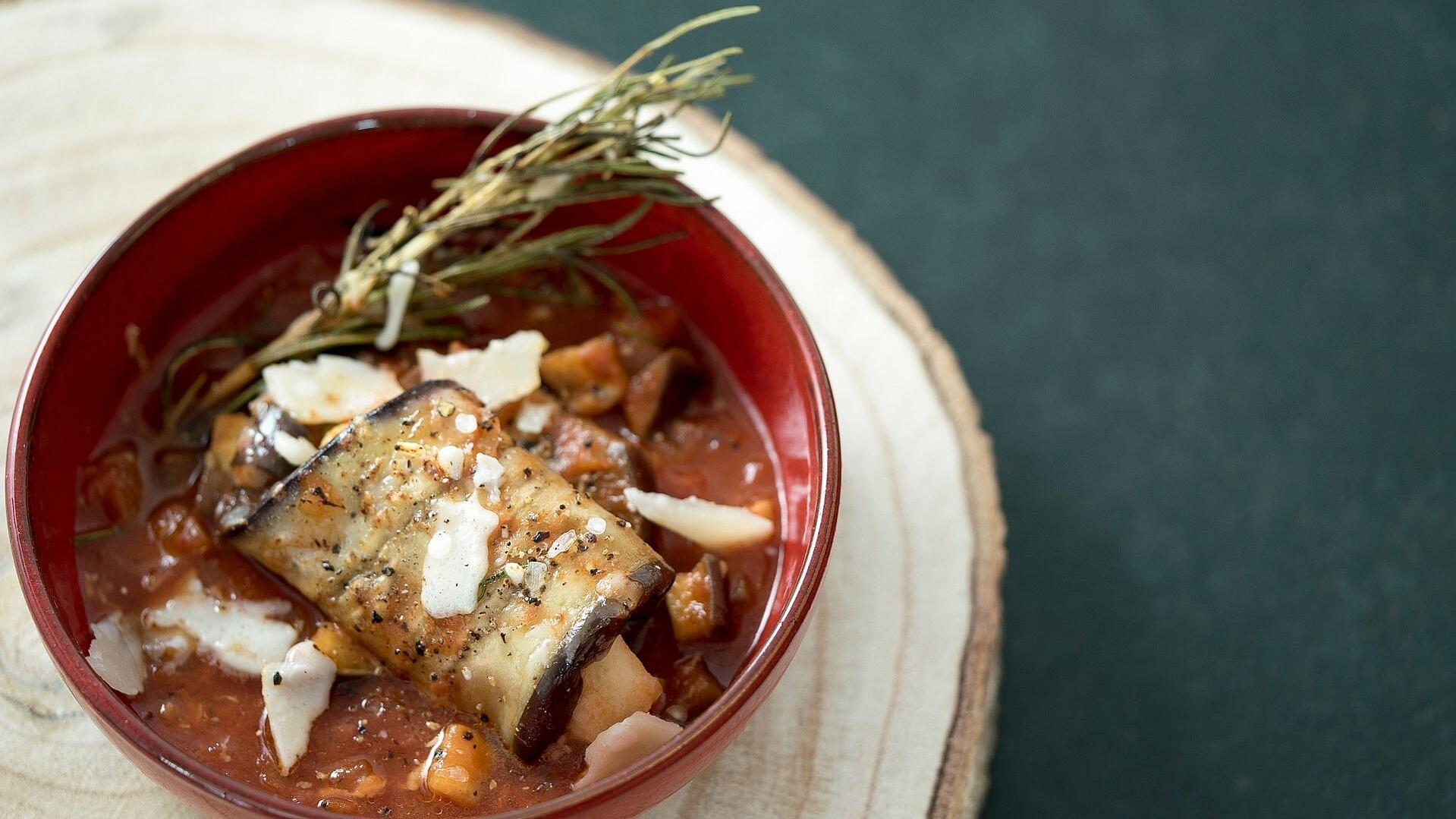 Ein geschmortes Auberginenröllchen in Tomatensauce in einer Schüssel