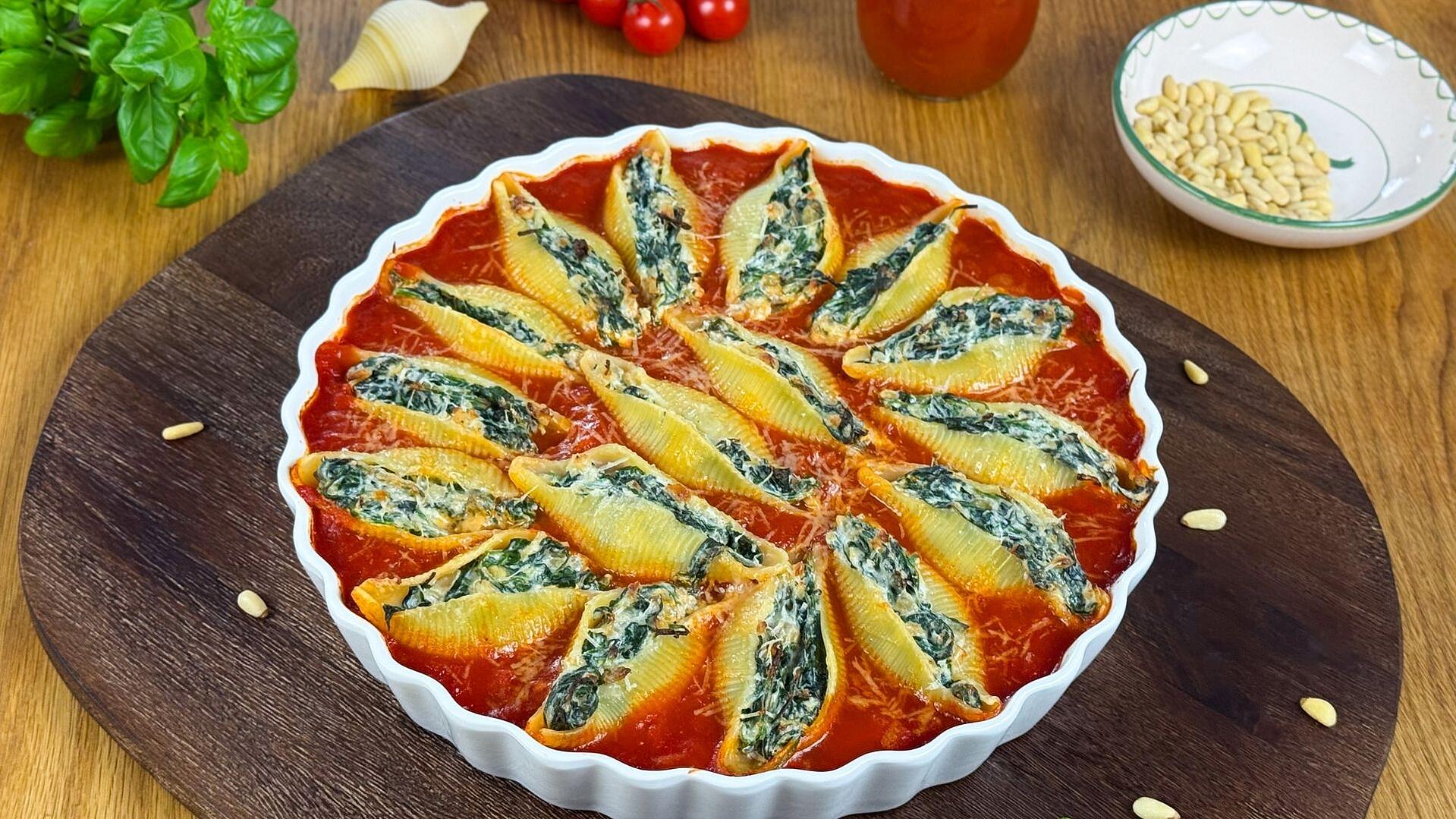 Gefüllte Muschelnudeln mit Spinat und Ricotta in Tomatensoße angerichtet in einer Auflaufform