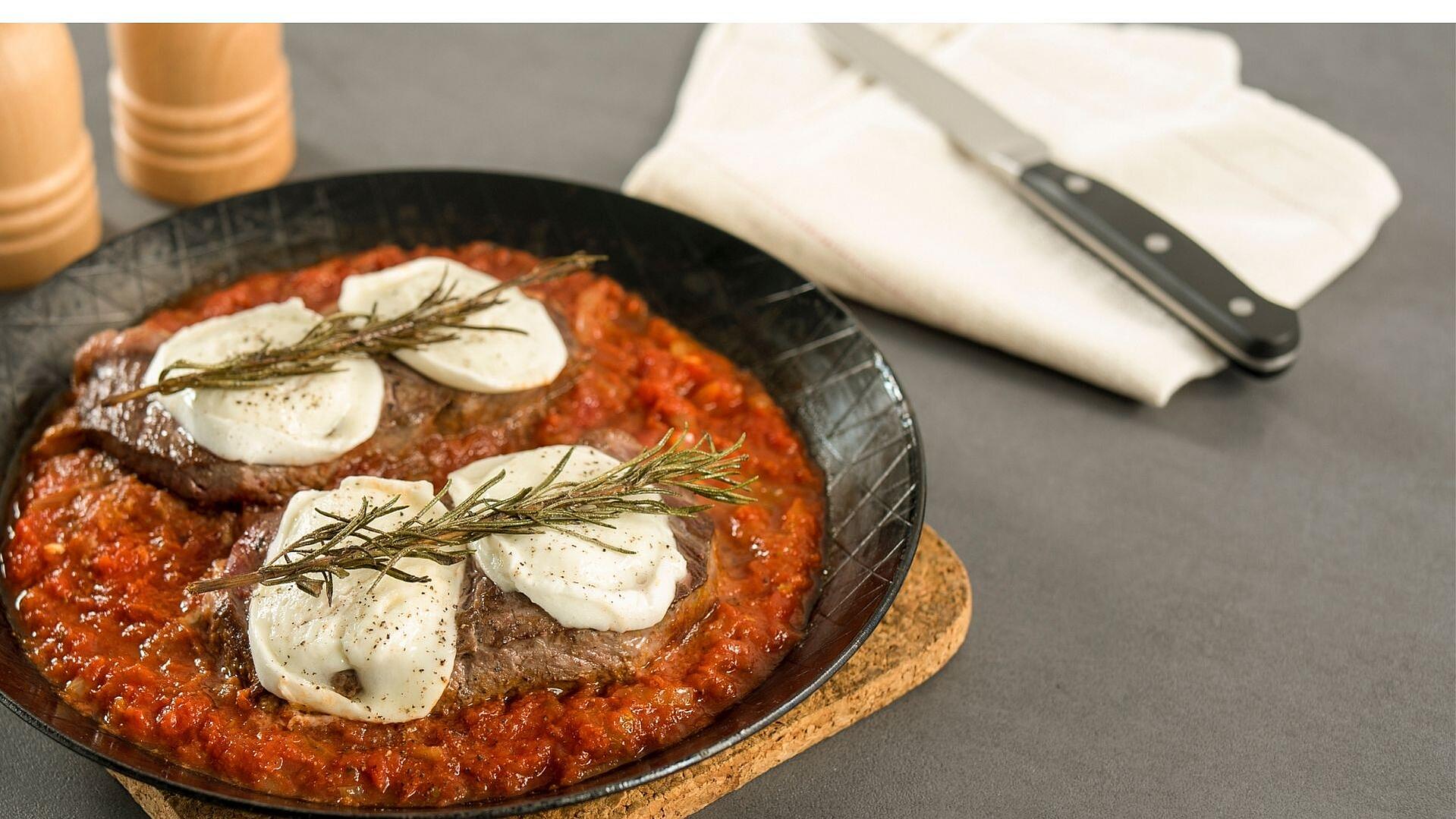 Eiserne Pfanne mit Bistecca con Pomodoro steht auf einem Tisch